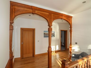 A hallway with wooden floors wooden doorways and decorative wooden archway at Bryn Mel Manor Straits View Menai Bridge