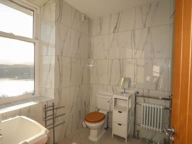 A bathroom with a toilet with wooden seat a white sink a small white storage unit and towel radiators at Bryn Mel Manor Straits View Menai Bridge