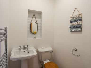 A bathroom with a pedestal sink and toilet with wooden seat at Bryn Mel Manor Straits View Menai Bridge