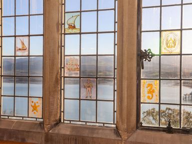 A window with small illustrated glass panels showing ships and sea creatures at Bryn Mel Manor Straits View in Menai Bridge