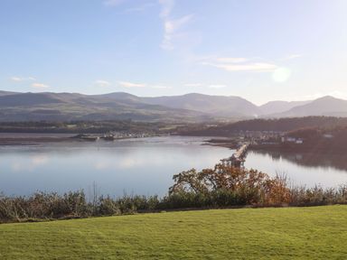 A view of a river with a pier and hills in the background at Bryn Mel Manor Straits View Menai Bridge