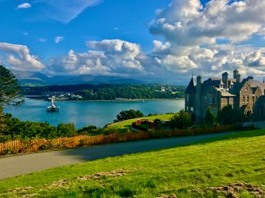 A large building on a hill overlooking water and distant mountains at Bryn Mel Manor Straits View Menai Bridge