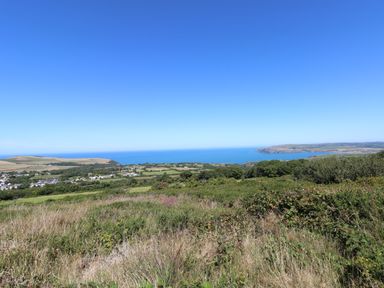 A coastal landscape with grassy fields and a village near the sea at Ty Rhydd in Newport Pembrokeshire
