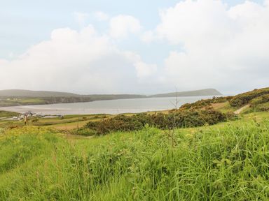 A coastline with hills grass and bushes overlooking a beach and sea at Ty Rhydd in Newport Pembrokeshire