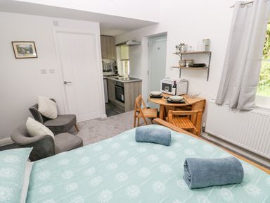 A bedroom with a bed towels on it two chairs a small dining table with two chairs and a kitchenette at Ty Rhydd in Newport Pembrokeshire