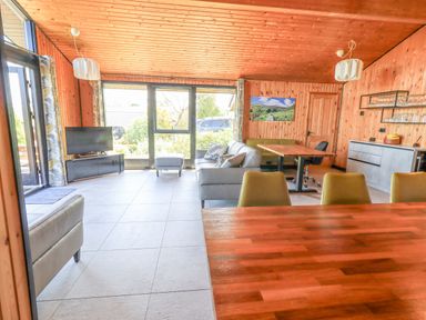 A living room with a sofa ottoman TV chairs tables and wooden walls at Greengarth in Yanwath near Penrith
