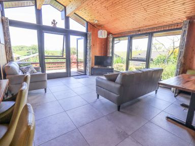 A living room with large windows two sofas a television and a wooden ceiling at Greengarth in Yanwath near Penrith