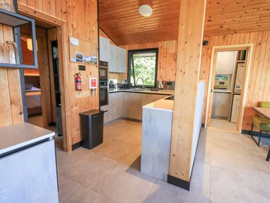 A kitchen with wooden walls and ceiling an oven sink window and a view into a laundry room at Greengarth in Yanwath near Penrith