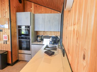 A kitchen with wooden walls a double oven a sink and kettles on the counter at Greengarth in Yanwath near Penrith