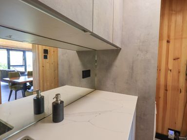 A kitchen countertop with a soap dispenser and cabinets above showing a dining area with chairs and table at Greengarth in Yanwath near Penrith