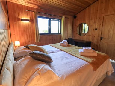 A bedroom with a bed with pillows and folded towels near a window and a desk with a round mirror at Greengarth in Yanwath near Penrith