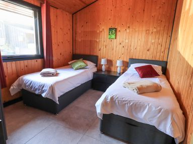 A bedroom with two single beds a window and wooden walls at Greengarth in Yanwath near Penrith