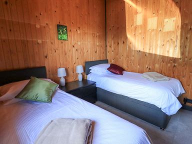A bedroom with two single beds a nightstand with two lamps and wooden panel walls at Greengarth in Yanwath near Penrith