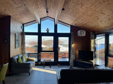 A living room with two sofas a television and large windows showing a snowy landscape at Greengarth in Yanwath near Penrith