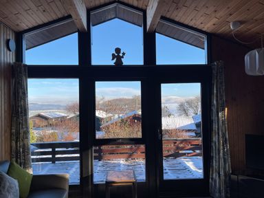 A room with large windows showing snow covered rooftops and trees at Greengarth in Yanwath near Penrith