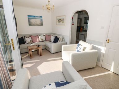 A living room with sofas cushions small nesting tables and framed pictures at Yacht Haven View in Neyland