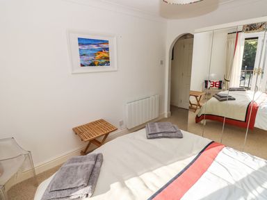 A bedroom with a bed with towels on it a small wooden stool a painting on the wall and mirrored wardrobes at Yacht Haven View in Neyland