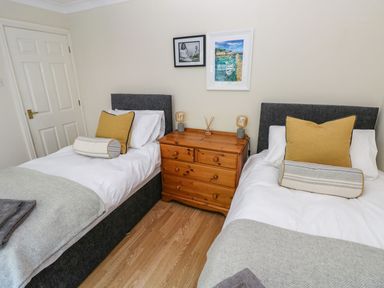 A bedroom with two single beds separated by a wooden chest of drawers at Yacht Haven View in Neyland