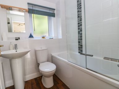 A bathroom with a pedestal sink toilet bathtub and frosted window at Yacht Haven View in Neyland