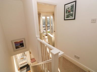 A staircase with white railing leading to a room with windows and chairs at Yacht Haven View in Neyland
