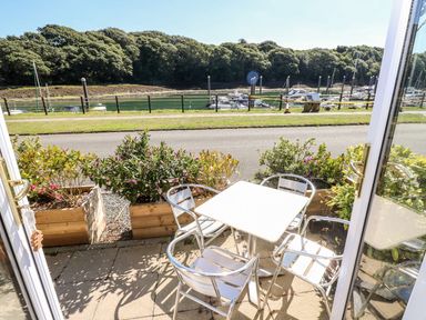 A patio with metal table and chairs overlooking a marina and trees at Yacht Haven View in Neyland