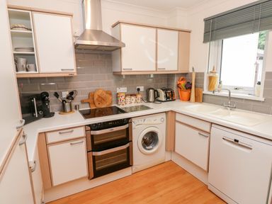 A kitchen with white cabinets appliances and a window with blinds at Yacht Haven View in Neyland