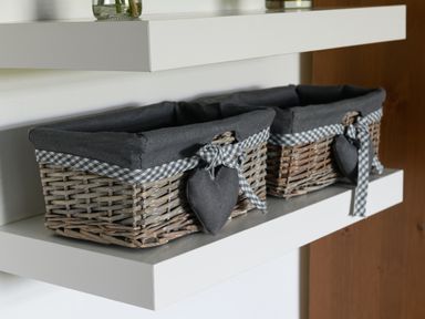 Two wicker baskets with black fabric liners and checkered bows on a white floating shelf at Ty Bach Beaumaris