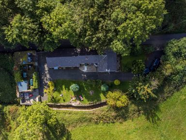 An aerial view of a rectangular house surrounded by trees a driveway and a lawn at Ty Bach - Beaumaris in Beaumaris