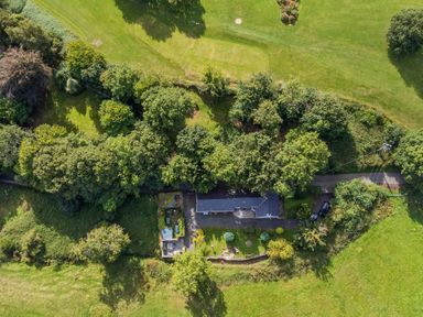 An aerial view of a house surrounded by trees and green fields at Ty Bach Beaumaris