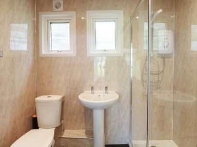 A bathroom with a toilet sink and a glass shower enclosure at 107 Kings Chalet Park in Cromer