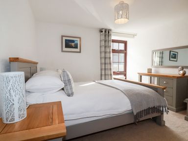 A bedroom with a bed table window and dresser at Great Meadow Barn in Crantock