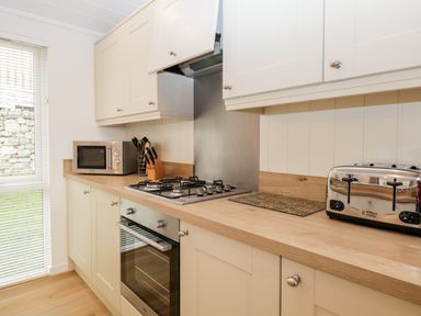 A kitchen with a gas stove oven microwave knife block and toaster at Hollytree Lodge Beckside 1 Limefitt Park near Windermere