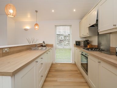 A kitchen with wooden countertops white cabinets a window at Hollytree Lodge Beckside 1 Limefitt Park near Windermere