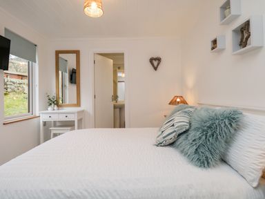 A bedroom with a large bed white bedding two pillows a white dressing table with a mirror and a window at Hollytree Lodge Beckside 1 Limefitt Park near Windermere