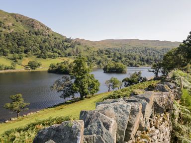 A stone wall overlooking a lake with trees and hills at Hollytree Lodge in Beckside 1 Limefitt Park near Windermere