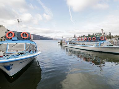 Two boats docked on a lake with hills and trees in the background at Hollytree Lodge Beckside 1 Limefitt Park near Windermere