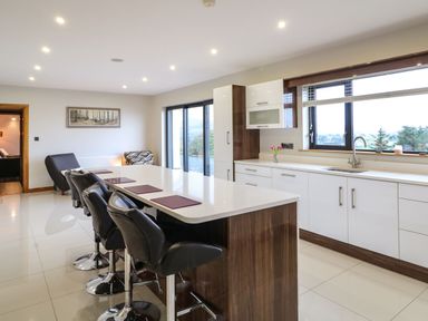 A kitchen with a long island and black bar stools at Upper Killult in Killult near Gortahork County Donegal
