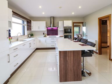 A kitchen with white cabinets a wooden island and black bar stools at Upper Killult in Killult near Gortahork County Donegal