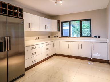 A kitchen with white cabinets stainless steel refrigerator and a window showing greenery at Upper Killult in Killult near Gortahork County Donegal