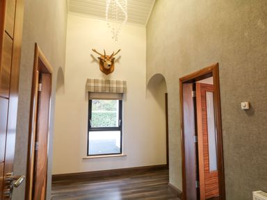 A hallway with a mounted deer head above a window and wooden doors at Upper Killult in Killult near Gortahork County Donegal