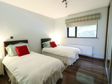 A bedroom with two single beds with white bedding and red pillows at Upper Killult in Killult near Gortahork County Donegal