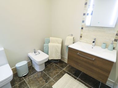 A bathroom with a toilet bidet towels sink and mirror at Upper Killult in Killult near Gortahork County Donegal