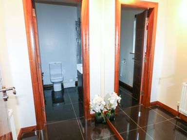 A hallway with two open wooden doors showing a bathroom with a toilet and sink and a room with a toilet paper holder and a radiator with a plant in front of a mirror at Upper Killult in Killult near Gortahork County Donegal