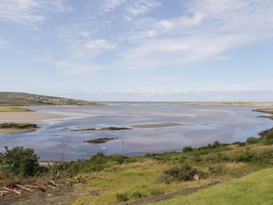 A coastal landscape with water and sandbanks and green grass in the foreground at Upper Killult in Killult near Gortahork County Donegal