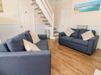 A room with two blue sofas with beige cushions wooden floor and a white staircase at Chalet 235 Wilsthorpe near Bridlington