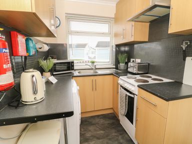 A kitchen with wooden cabinets and black countertops at Chalet 235 Wilsthorpe near Bridlington