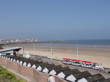 A beach with a toy train on a promenade and rows of small huts at Chalet 235 in Wilsthorpe near Bridlington