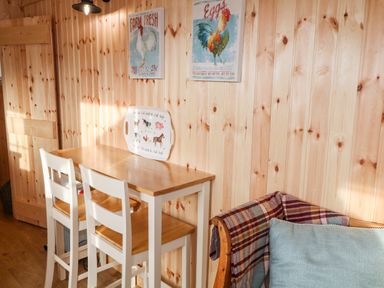 A wooden dining table with two white chairs and farmhouse-themed wall decor in a room at Shepherds Retreat Glenlark Gortin near Greencastle