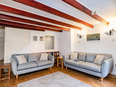 A living room with two grey sofas and wooden beams on the ceiling at Honey Cottage in Port Isaac