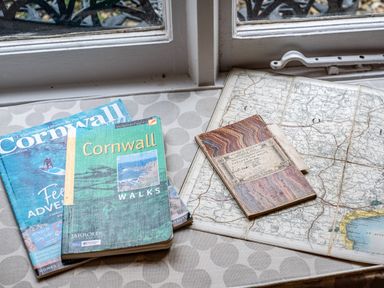 A window sill with maps and guidebooks of Cornwall at Honey Cottage in Port Isaac